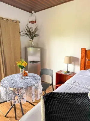 a room with a table and a bed and a kitchen at Refugio Las Cortezas in Tapantí