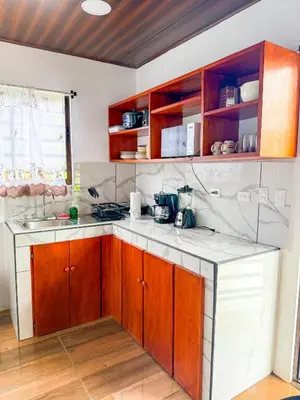 a kitchen with wooden cabinets and white counter tops at Refugio Las Cortezas in Tapantí