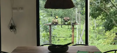 a dining room table with a view of a window at Private rainforest villa up to 8 guests w jacuzzi near Rio Celeste in Upala