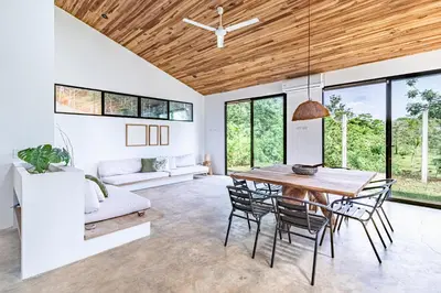 a living room with a wooden ceiling and a table and chairs at Private rainforest villa up to 8 guests w jacuzzi near Rio Celeste in Upala