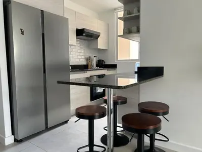 a kitchen with a counter with stools and a refrigerator at Charming Apartment in Curridabat in Granadilla