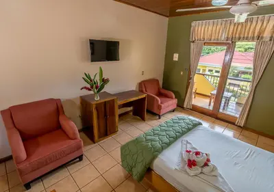 a bedroom with a bed and a chair and a tv at Hotel Manuel Antonio in Manuel Antonio