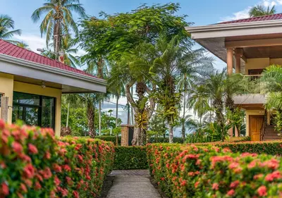 a house with a garden with flowers and trees at Hotel Manuel Antonio in Manuel Antonio