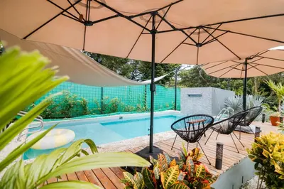a patio with two umbrellas and a swimming pool at Casa Ola Ini Studio Playa Grande in Playa Grande