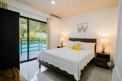 a bedroom with a bed with two lamps and a balcony at Casa Ola Ini Studio Playa Grande in Playa Grande