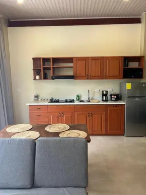 a kitchen with wooden cabinets and a table with chairs at Apartamentos Margarita in Quepos