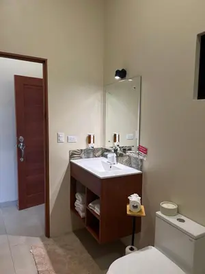 a bathroom with a sink and a mirror and a toilet at Apartamentos Margarita in Quepos
