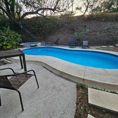 a swimming pool with two chairs and a table at Apartamento moderno con vista al río, piscinas y gym Costa Rica in Santa Ana