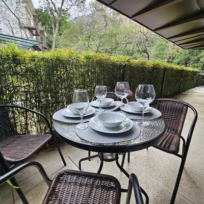 a table with chairs and wine glasses on a patio at Apartamento moderno con vista al río, piscinas y gym Costa Rica in Santa Ana