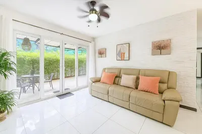 a living room with a couch and a patio at Apartamento moderno con vista al río, piscinas y gym Costa Rica in Santa Ana