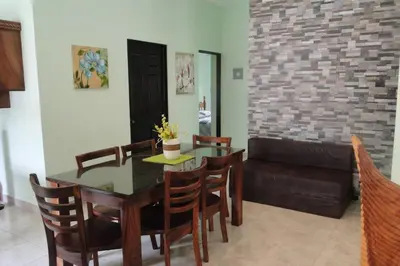 a dining room with a table and chairs and a couch at Beach House In Punta Leona with private Pool in Punta Leona