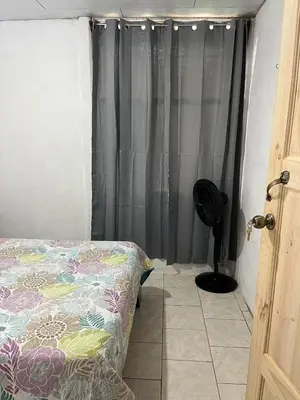a bedroom with a bed and a black curtain at El Jardín de Tere in Bijagua