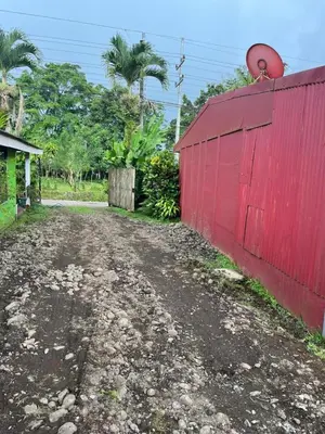 a red fence next to a dirt road at El Jardín de Tere in Bijagua