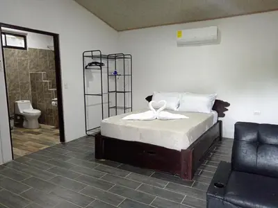 a bedroom with a bed and a bathroom with a toilet at Pino Lodge, Río Celeste in Upala