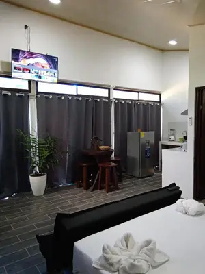 a room with black curtains and a table and a kitchen at Pino Lodge, Río Celeste in Upala