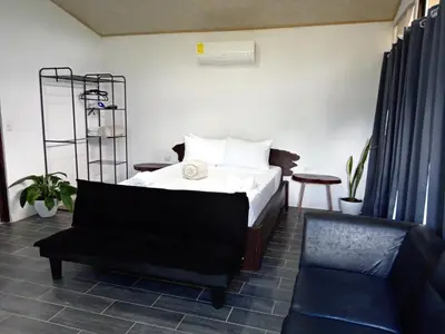 a bedroom with a bed and a chair and a couch at Pino Lodge, Río Celeste in Upala