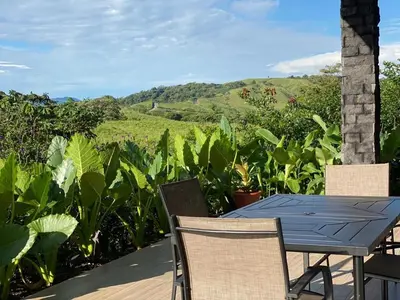 a table and chairs on a deck with a view of a field at Villa Guarumo in Santa Eulalia