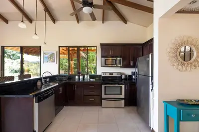 a kitchen with wooden cabinets and stainless steel appliances at Casa Mareas in Dominicalito