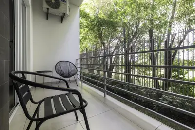 a balcony with two chairs and a window with trees at Corporate Stays Urban Flats Studio in San Rafael