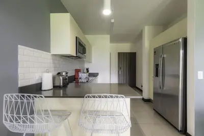 a kitchen with a refrigerator and two chairs in it at Corporate Stays Urban Flats Studio in San Rafael