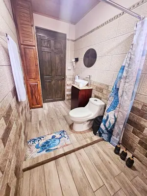 a bathroom with a toilet and a wooden door at Kame House, Tortuguero in Tortuguero