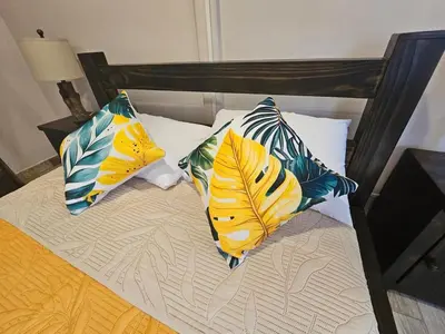 a bed with three pillows on top of it at Kame House, Tortuguero in Tortuguero