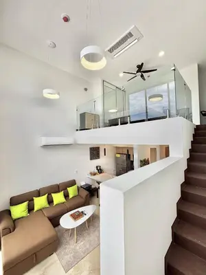 a living room with a couch and a staircase at Brand New Loft Few Steps From The Beach in Jacó