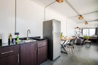 a kitchen with a refrigerator and a dining room at The DEN in Tamarindo