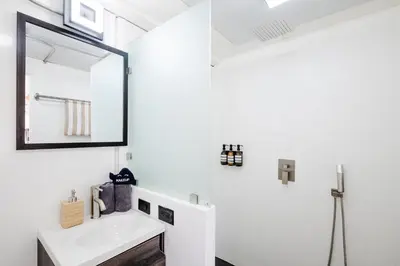 a white bathroom with a sink and a mirror at The DEN in Tamarindo