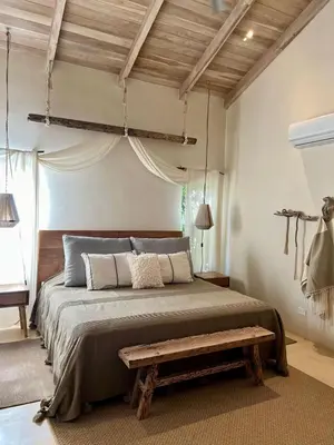 a bedroom with a large bed with a bench on it at Gorgeous beachfront villa with private pool in Santa Teresa Beach