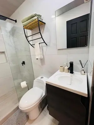 a white bathroom with a toilet and a sink at Kens Lower department in Quepos
