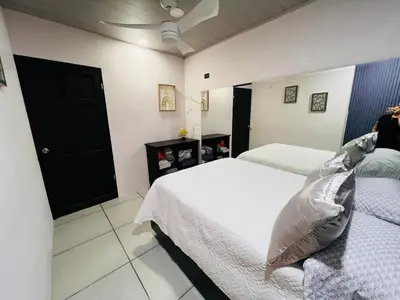 a bedroom with two beds and a black door at Kens Lower department in Quepos
