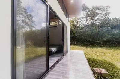 a glass extension of a house with a porch at Newly built Surf Hideaway in Avellanas Beach in Playa Avellana