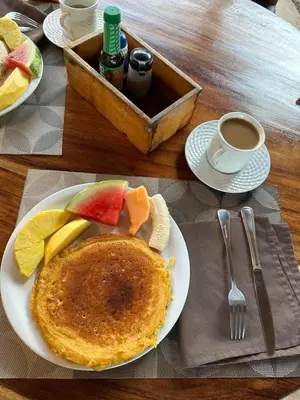 a plate of pancakes and fruit and a cup of coffee at Poolside Unit at Beachfront Hotel in Sámara