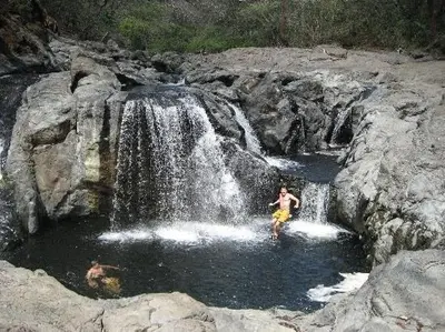 a man standing in front of a waterfall at Tree House Inn Ocean Front Unit #2 in Sámara