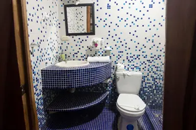 a blue and white bathroom with a toilet and a sink at Samara Tree House Inn Unit 4 in Sámara