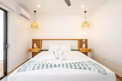 a bedroom with a white bed with two pendant lights at Casa Peace with salt water pool 4BR 4BR in Tamarindo
