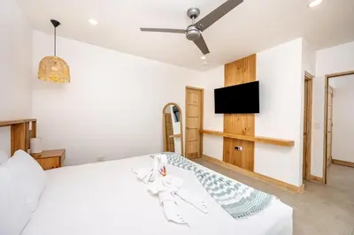 a bedroom with a white bed and a flat screen tv at Casa Peace with salt water pool 4BR 4BR in Tamarindo