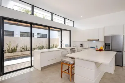 a kitchen with white cabinets and a large window at Casa Peace with salt water pool 4BR 4BR in Tamarindo