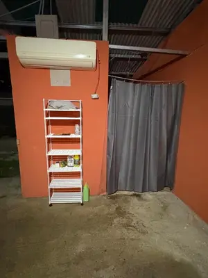 a room with an orange wall with a heater and a curtain at Camping y hospedaje playa azul in Tarcoles