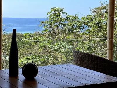 a table with a vase sitting on top of a balcony at Ocean view Jungle Nest - 2min from the beach in Santa Teresa Beach