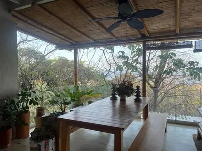 a wooden table in a room with a ceiling fan at Ocean view Jungle Nest - 2min from the beach in Santa Teresa Beach