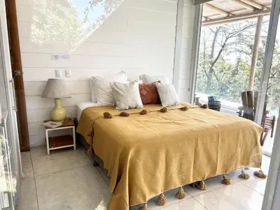 a bedroom with a large bed with a large window at Ocean view Jungle Nest - 2min from the beach in Santa Teresa Beach