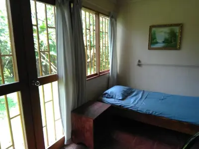 a small bedroom with a bed and two windows at CASA QUEPOS- Private House & Farm For 8-31 Guests in Quepos
