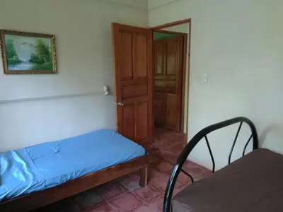 a small bedroom with a bed and a wooden door at CASA QUEPOS- Private House & Farm For 8-31 Guests in Quepos