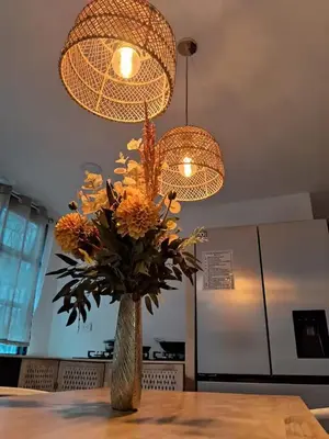 a vase of flowers on a table under a chandelier at Habitaciones Smith in San José
