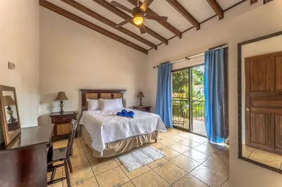 a bedroom with a bed and a table and a window at Sunset Villa, comfortable house steps from the beach in Bejuco