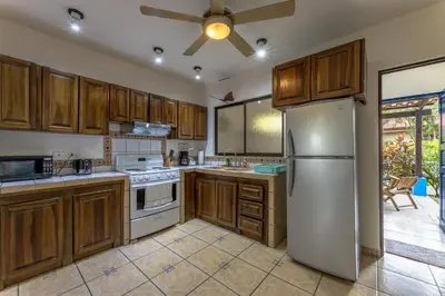 a kitchen with wooden cabinets and a stainless steel refrigerator at Sunset Villa, comfortable house steps from the beach in Bejuco
