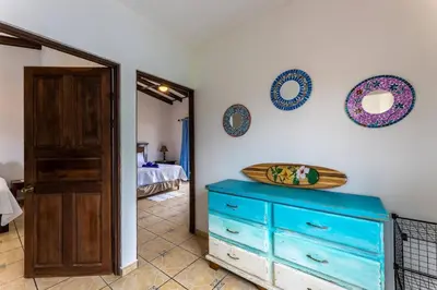 a room with a blue dresser and a surfboard on a wall at Sunset Villa, comfortable house steps from the beach in Bejuco