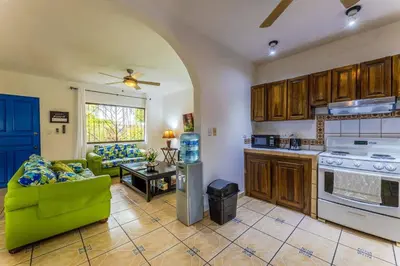 a living room with a couch and a kitchen at Sunset Villa, comfortable house steps from the beach in Bejuco